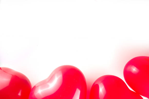 Red heart shape balloon in mid-air against blue background with copy space.