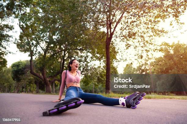 Young Female Skater Laughing While Sitting On The Road After The Fall Stock Photo - Download Image Now