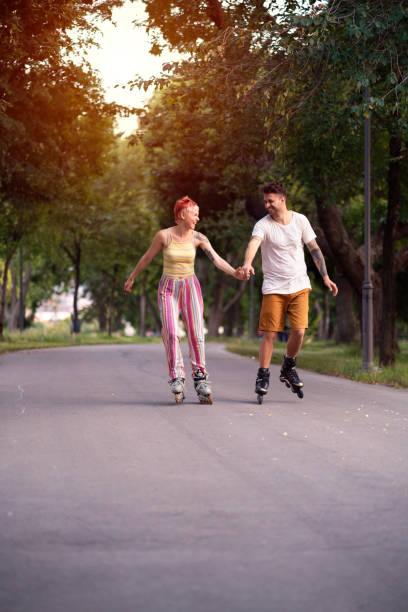 istock Smiling couple holding hands and rollerblading in the park together 1365417991