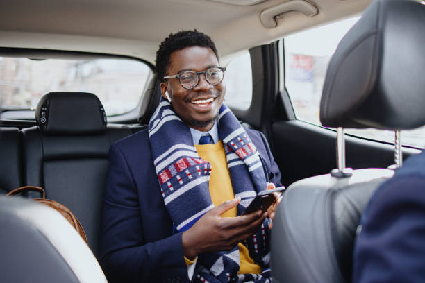 homme d’affaires heureux et souriant tapant un message au téléphone tout en étant assis dans une taxe - seat belt audio photos et images de collection