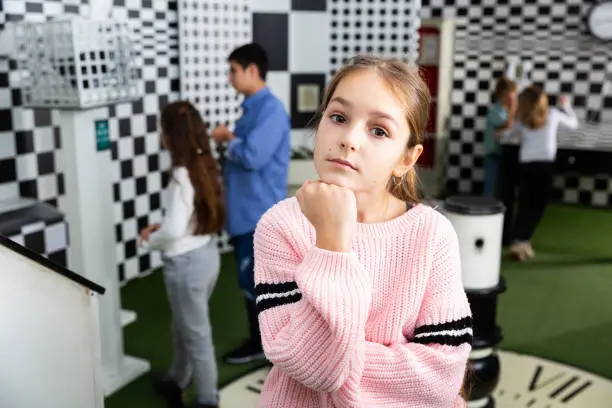 Photo of Pensive girl solving conundrum in quest room designed as chessboard