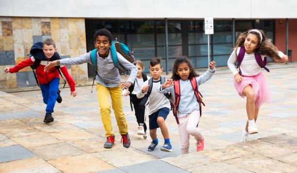 istock Group of cheerful tweenagers running in school yard after lessons 1365425027