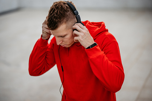A handsome young athlete listening to music after a workout outdoors.