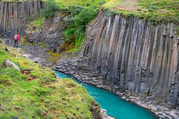 woman standing at edge of Beautiful Studlagil canyon with basalt columns in Jokuldalur Valley,   that is in East Iceland.