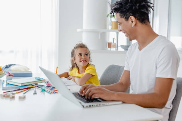 istock Young father is working from home and his daughter is writing homework next to him 1365427019