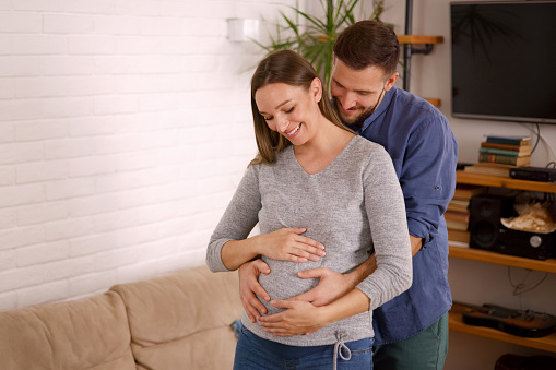 Happy husband caresses the belly of his pregnant wife