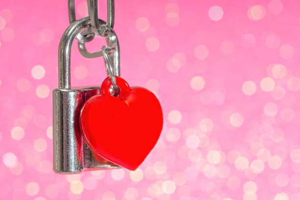 istock Locked padlock with a red plastic heart on pink 1365431028