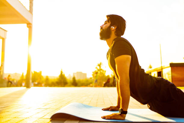 uomo ispanico in t-shirt di cotone nero pronto per lo yoga al tramonto nel parco estivo all'aperto luci dorate - sunset yoga young men caucasian foto e immagini stock