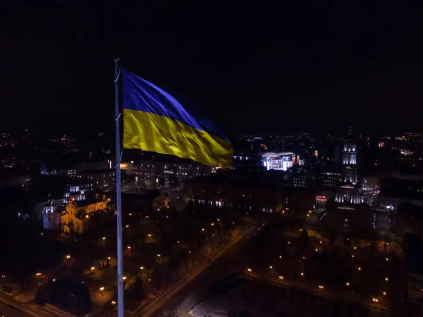 Photo of Ukrainian flag in the wind. Blue Yellow flag Against the big city at night