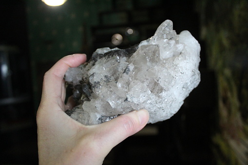 photo of a beautiful unprocessed stone. a woman holds a crystal in her hand. large natural rhinestone. white, transparent color. inclusions of yellow and black.
