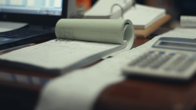 Old calculator and receipts sit on accountant desk in Indian office by computer