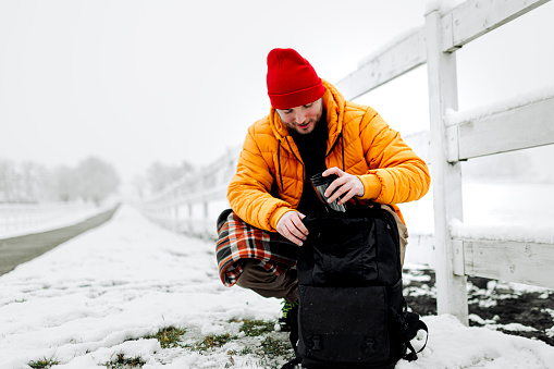 Young man packing backpack for snowy day