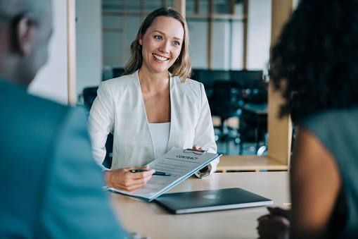 Couple sitting at desk in the bank and signing loan agreement.