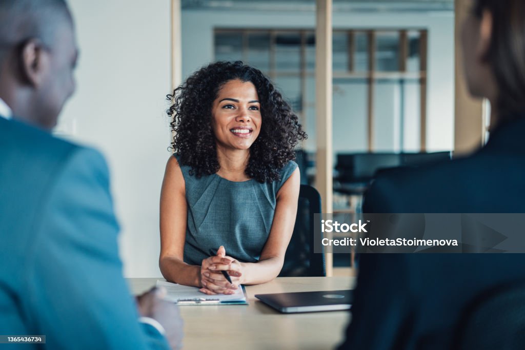 Group of business persons talking in the office. Shot of group of business persons in business meeting. Three entrepreneurs on meeting in board room. Corporate business team on meeting in modern office. Female manager discussing new project with her colleagues. Company owner on a meeting with two of her employees in her office. Advice Stock Photo