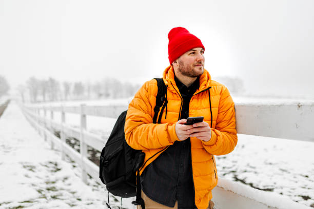 Young man using smartphone in nature on a snowy day Young man using smartphone in nature on a snowy day extreme terrain stock pictures, royalty-free photos & images