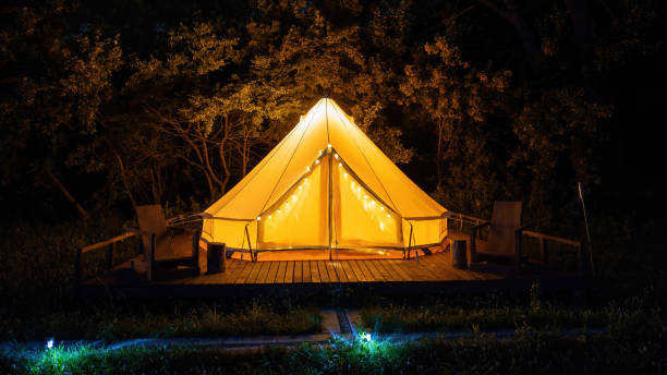 Glamping at night, glowing tent with chairs in front of it Glamping at night, glowing tent with chairs in front of it, nightlights party rentals stock pictures, royalty-free photos & images