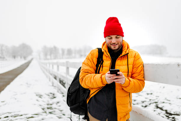 Young man using smartphone in nature on a snowy day