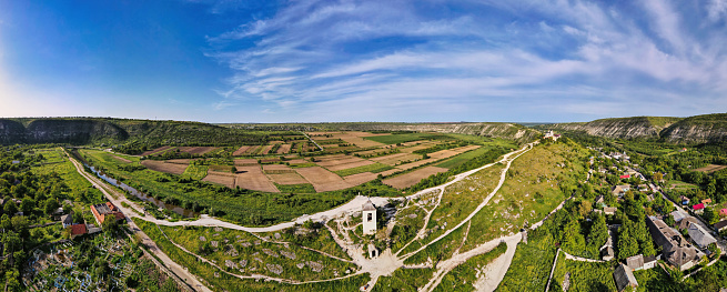 Aerial drone panoramic view of nature, church, valley with river, hills and fields, multiple greenery, village, Moldova