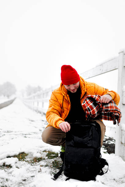 istock Young man packing backpack for snowy day 1365442362