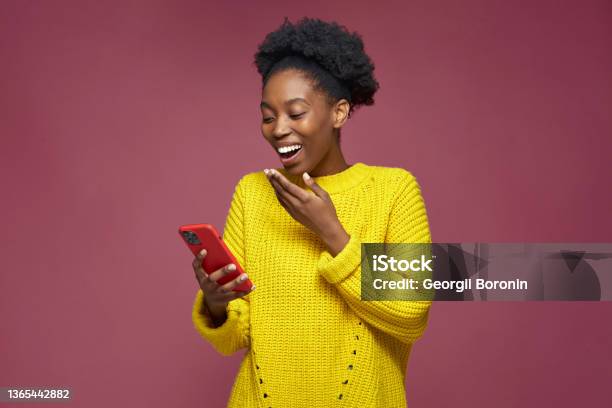 Laughing African American Girl Hold Phone Watching Funny Videos In Social Network Having Fun Surprised By Good News Stock Photo - Download Image Now