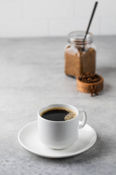 istock Black coffee in a white mug on a saucer on a grey table. Copy space. 1365442886