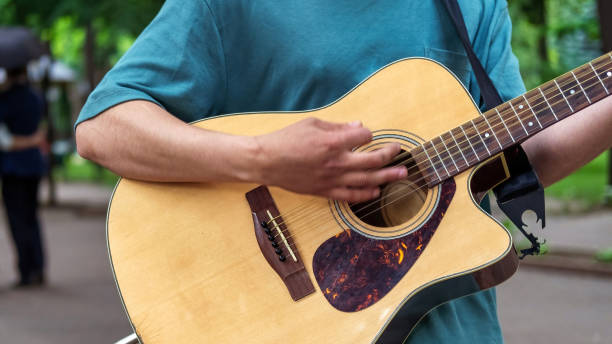 istock Man playing guitar outdoors in a park 1365442892