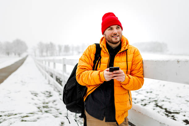 istock Young man using smartphone in nature on a snowy day 1365442910