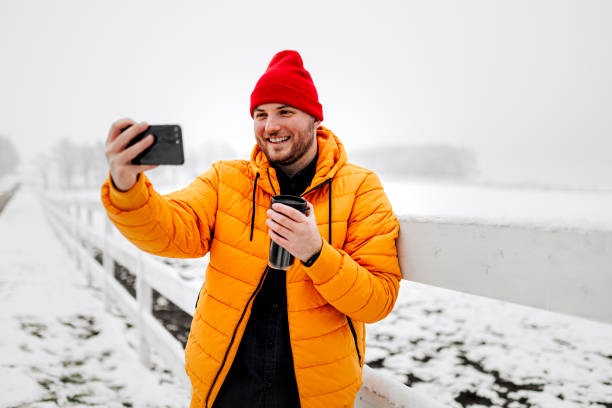 istock Happy young man drinking hot drink and having video call with friends 1365443642