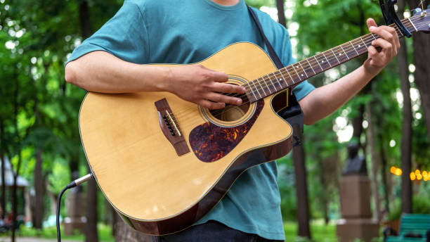 istock Man playing guitar outdoors in a park 1365443980