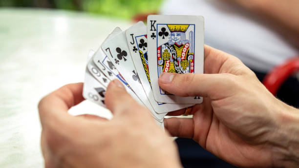 istock A man playing cards with other people holding a deck 1365444104
