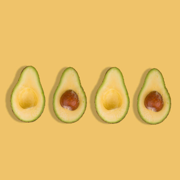 istock Sliced avocado on pastel yellow background. Top view. 1365444313