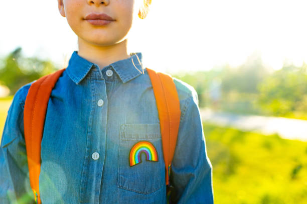 girl in denim t-shirt with rainbow symbol wear backpack in summer park outdoor girl in denim t-shirt with rainbow symbol wear backpack in summer park outdoor. childhood stock pictures, royalty-free photos & images