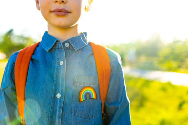 dziewczyna w dżinsowym t-shircie z tęczowym symbolem nosić plecak w letnim parku na zewnątrz - childhood zdjęcia i obrazy z banku zdjęć