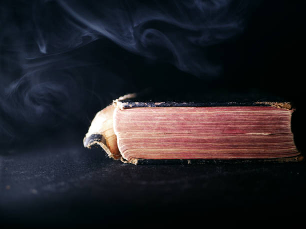 istock Old worn book on dark smoke background 1365445840