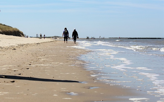 Nieuwvliet, Holland - may 5,  2016: people are walking at  the beach near the waterline at the dutch coast in zeeland in springtime