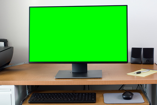 Home office with large PC monitor computer screen on the office desk. Green screen for easier copy space.