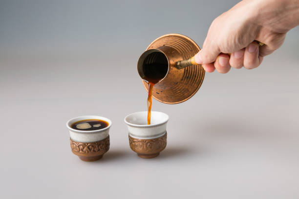 istock A man's hand pours black cezve coffee into traditional Turkish coffee cups. 1365456950