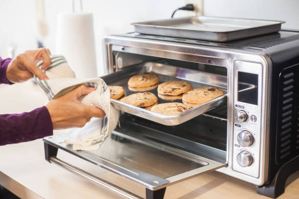 hornear galletas en un horno tostador - bandeja de horno fotografías e imágenes de stock