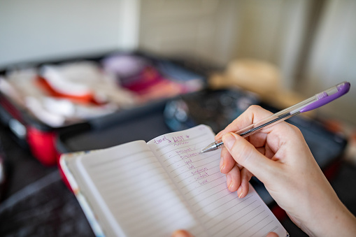 Young woman checks list for packing suitcase for vacation