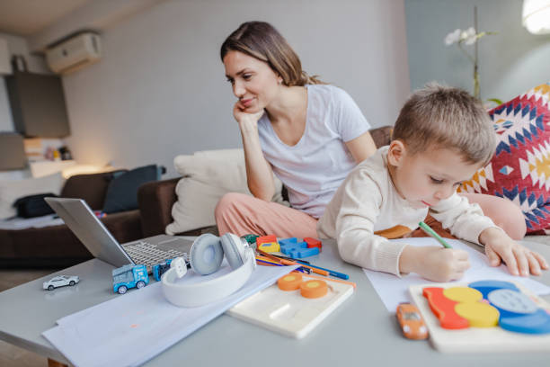 istock Young mother works on laptop at home 1365468388