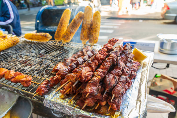 istock Meat kebabs and corn on the cob at a sidewalk food stand. 1365468439