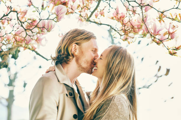 Happy romantic couple kissing under blooming tree