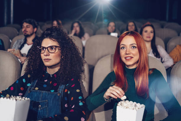Close up of a group of friends enjoying a movie in the cinema Group of young people sitting in modern cinema and watching funny movie. They are happy and laughing. video productions stock pictures, royalty-free photos & images