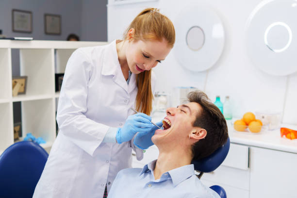 istock Dentist smiling and examining teeth of patient 1365474570