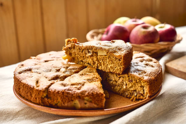 tranche de gâteau aux pommes maison charlotte ou tarte aux pommes éponge américaine aux noix et pommes rouges mûres sur la table avec nappe en lin. alimentation saine de saison. - cake pie apple pie apple photos et images de collection