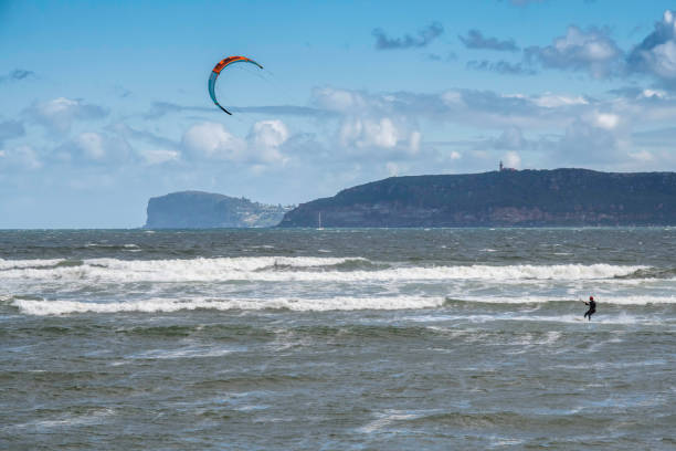 Windsurfers riding the waves on a wild day at the beach stock photo