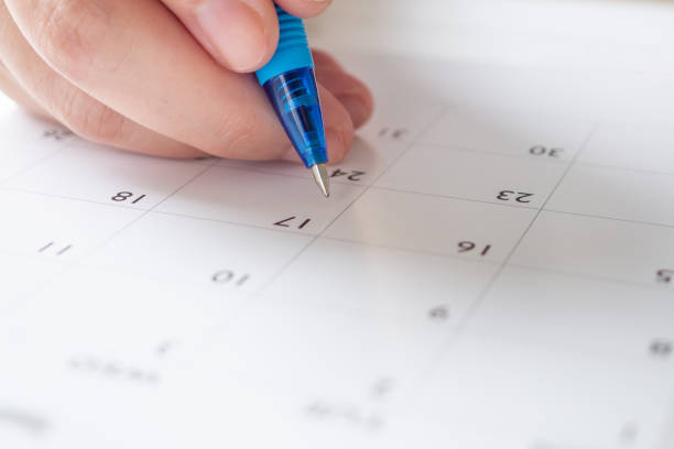 Woman hand with pen writing on calendar date business planning appointment meeting concept stock photo