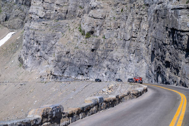 관광객들로 가득 찬 빨간 방해기 투어 버스가 빙하 국립 공원의 태양 도로로 가는 길을 만듭니다. - us glacier national park montana bus park 뉴스 사진 이미지