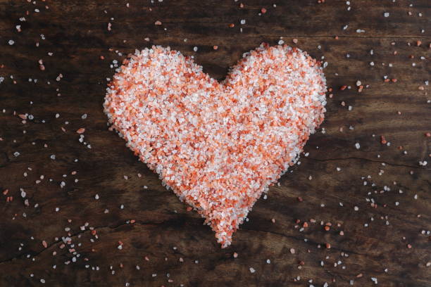소박한 나무 테이블에 분홍색 암염으로 형성된 심장 모양 - affectionate desire beauty brown 뉴스 사진 이미지