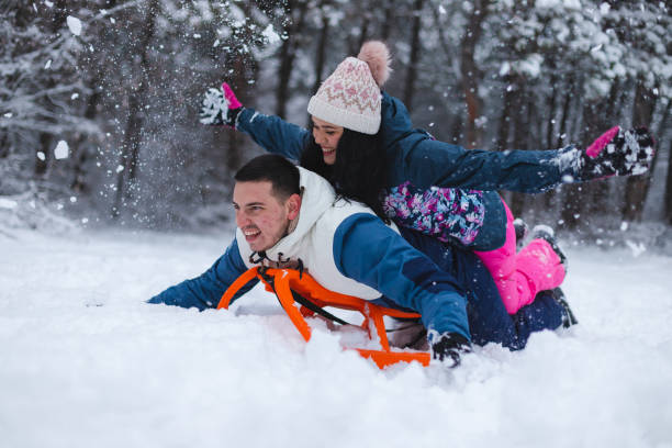 istock Young beautiful and romantic couple having fun in the snow while laying on a sled 1365496183